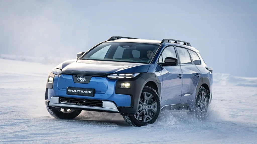 Blå Subaru E-Outback kjører gjennom snø og virvler opp pudder.