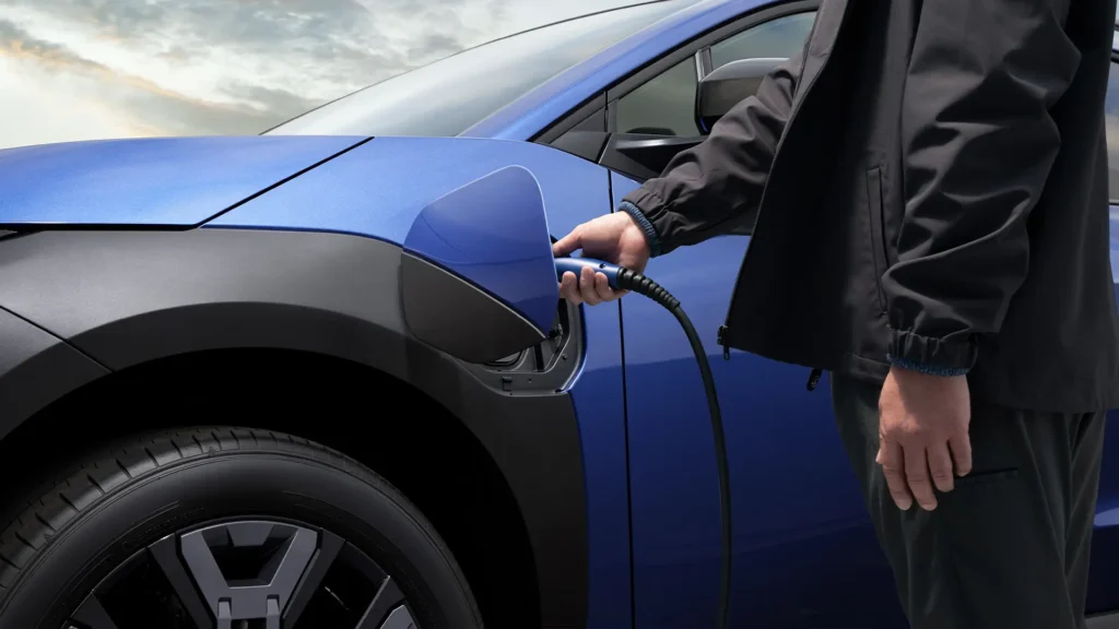 En person lader en blå elbil.