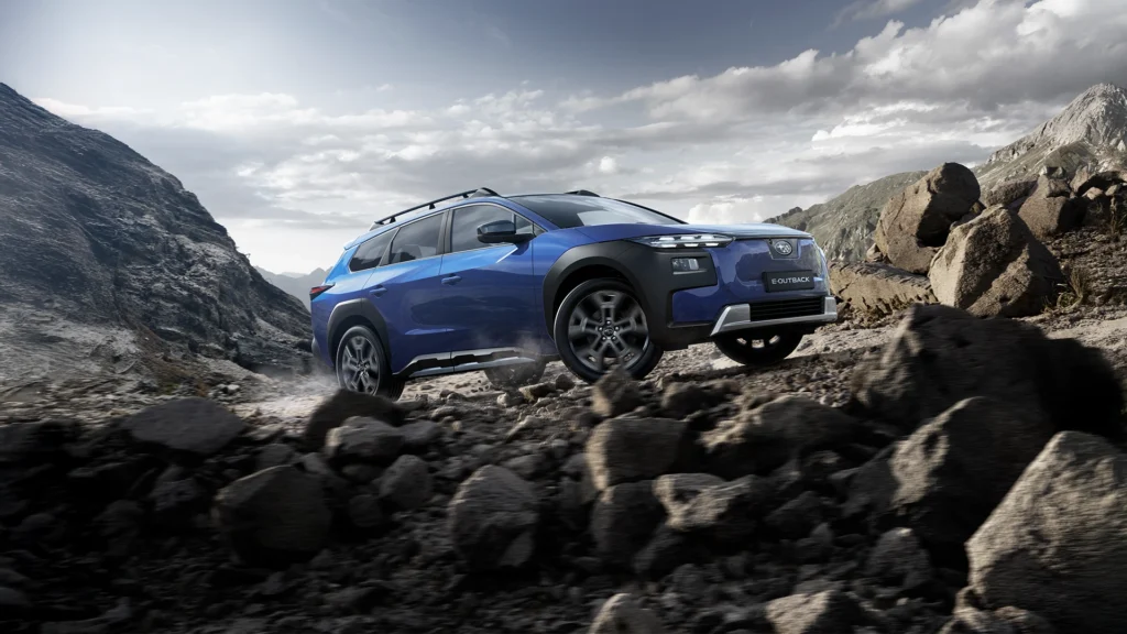 Blå Subaru E-Outback kjører på steinete terreng i fjellandskap.