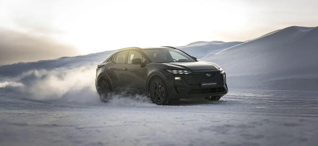 SUV kjører gjennom snødekt landskap under overskyet himmel.